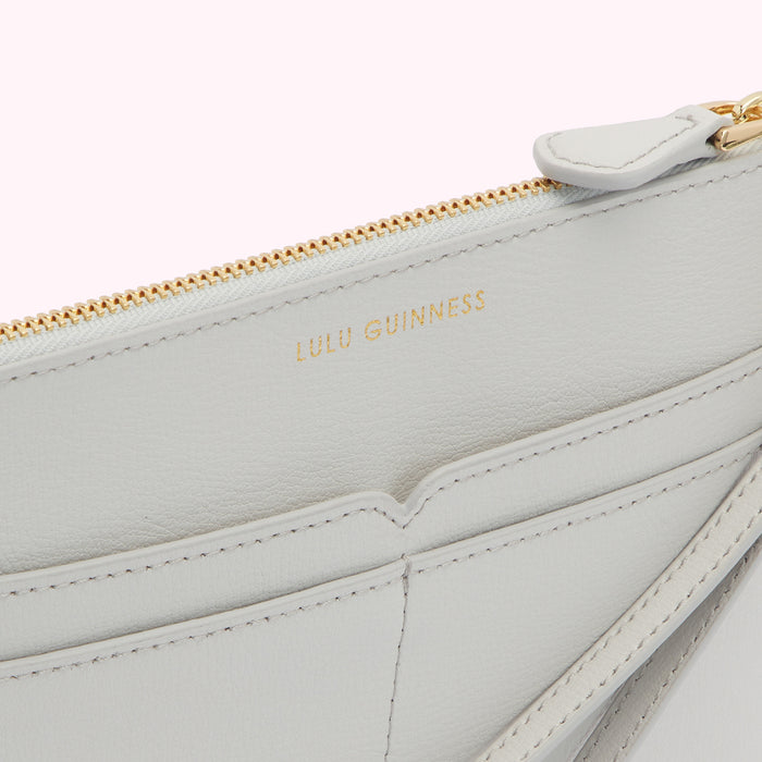 Close-up view of the inside of a light grey Lulu Guinness zip-around wallet, showing the brand name and interior compartments.