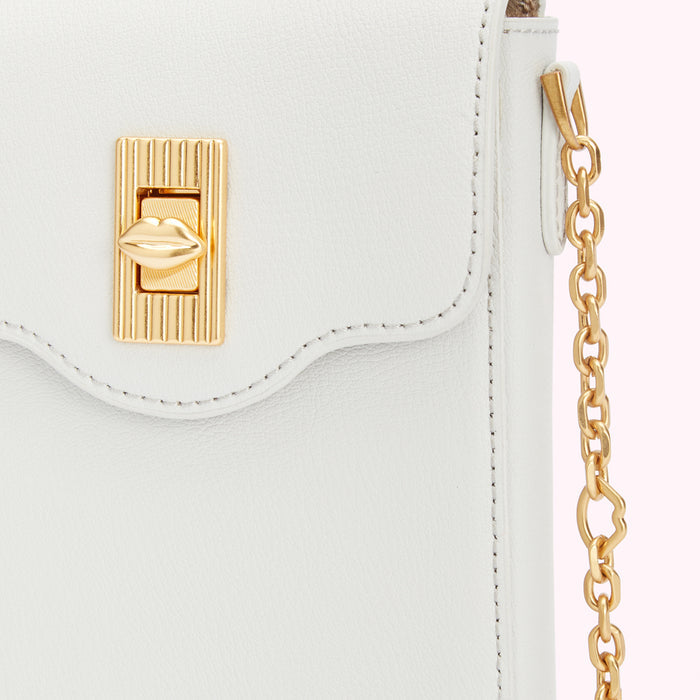 Close-up of a white leather handbag with a gold lip-shaped clasp and gold chain strap.