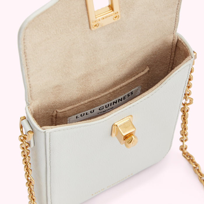 Pale grey Lulu Guinness crossbody bag with gold clasp and chain strap, open to reveal beige interior.