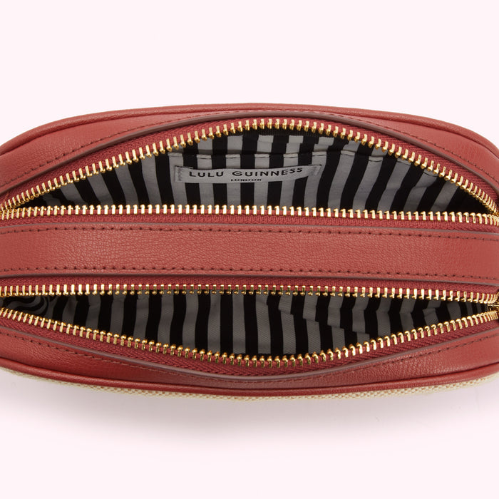 Interior view of a Lulu Guinness London handbag, showing the red leather exterior and black and white striped fabric lining.