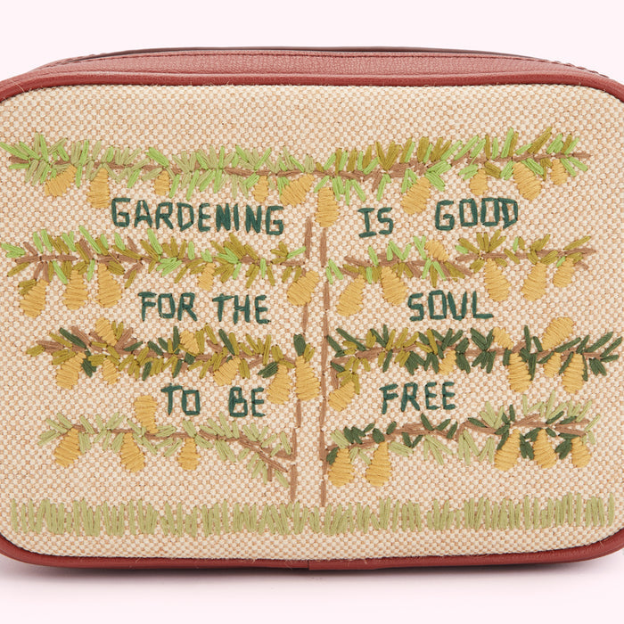 Beige crossbody bag with embroidered trees and the text "Gardening is good for the soul to be free".