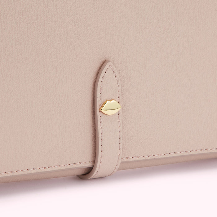 Close-up of a light pink leather wallet with a gold lip-shaped clasp.