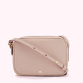 A blush pink crossbody bag with a gold logo and clasp.