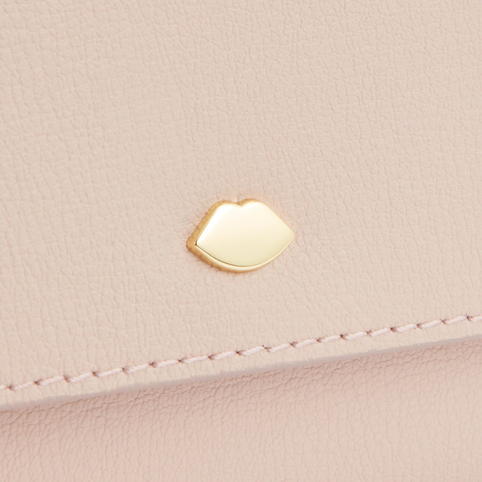 Close-up of a pale pink leather purse with a gold lip-shaped detail.