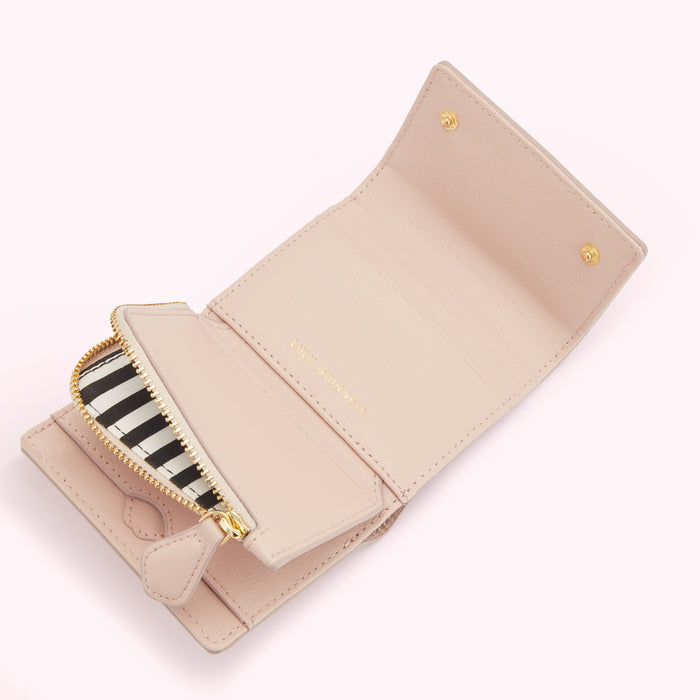 Open blush pink leather wallet with a black and white striped zipper.