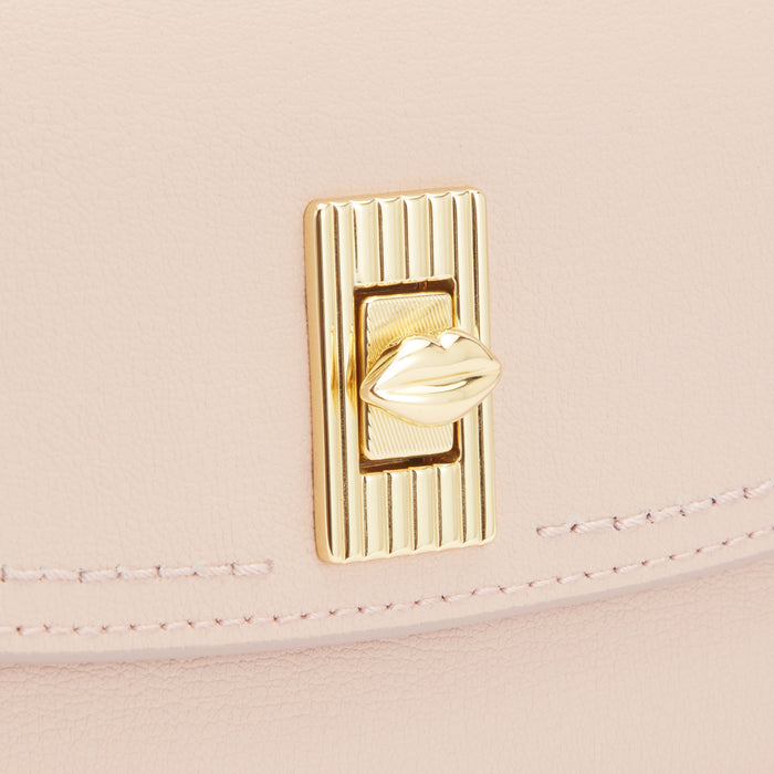 Close-up of a light pink leather handbag's clasp, featuring a gold lip-shaped detail.