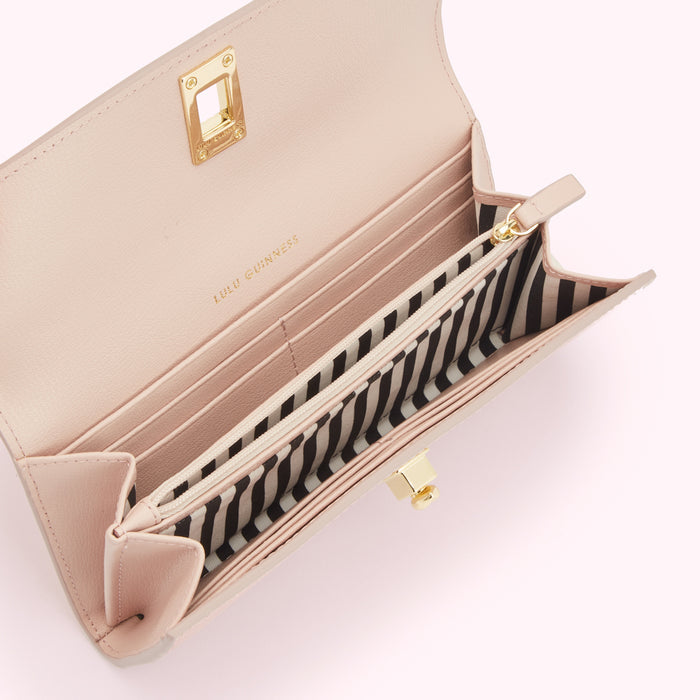 Open blush pink Lulu Guinness wallet with black and white striped interior.