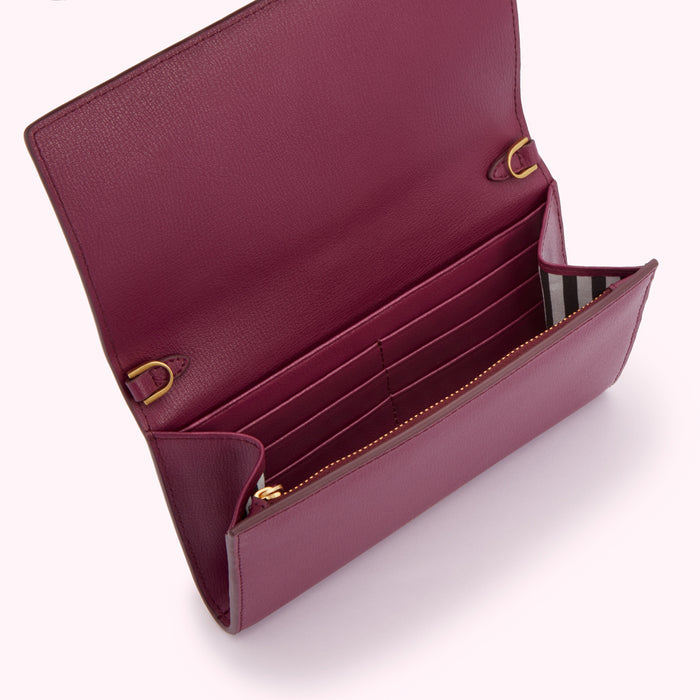Open purple leather wallet with gold hardware and black and white striped interior.