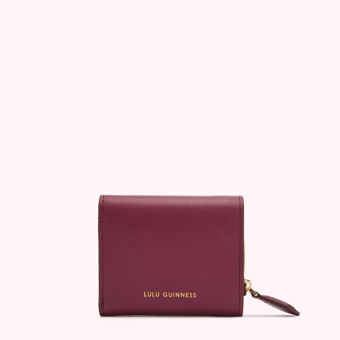Burgundy Lulu Guinness zip-around wallet against a white background.