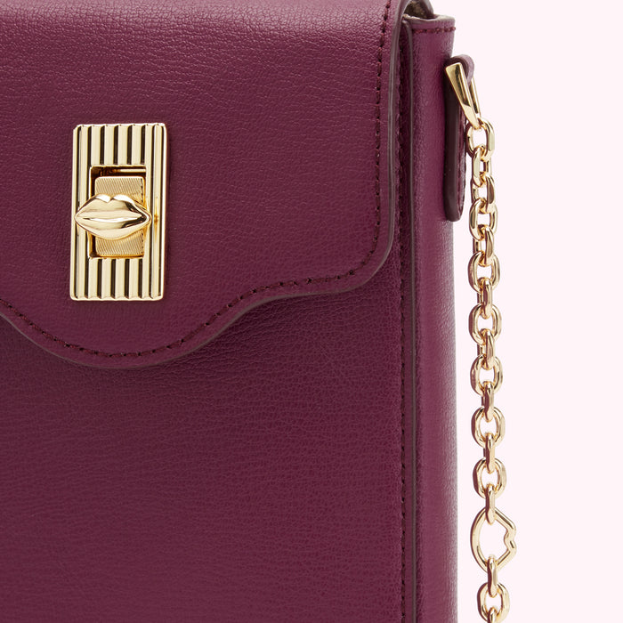 Close-up of a burgundy leather crossbody bag with a gold lip-shaped clasp and chain strap.
