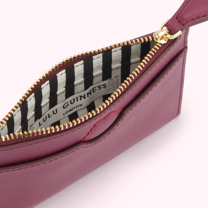 Close-up view of a burgundy Lulu Guinness zip-around purse with a black and white striped interior.