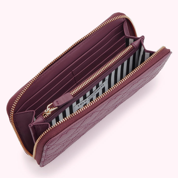 Open purple Lulu Guinness zip-around wallet with quilted pattern and black and white striped interior.