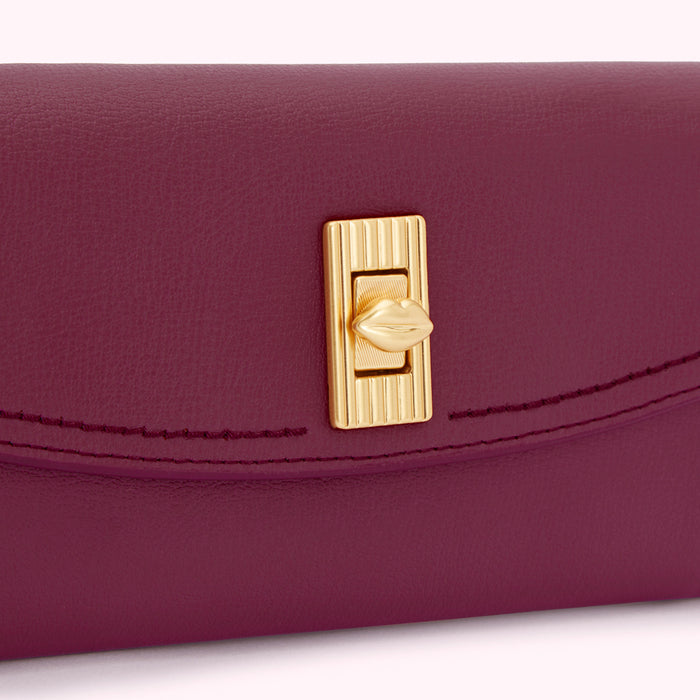 Close-up of a burgundy leather wallet with a gold lip-shaped clasp.