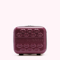 A burgundy Lulu Guinness rolling suitcase adorned with embossed lips.