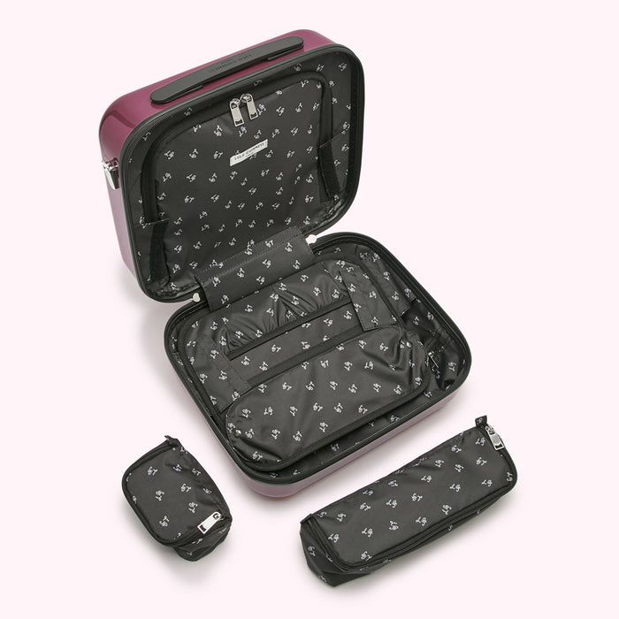 A burgundy hard-shell carry-on suitcase is open to reveal its interior compartments and organization features. Two smaller matching zippered pouches are shown next to the suitcase.