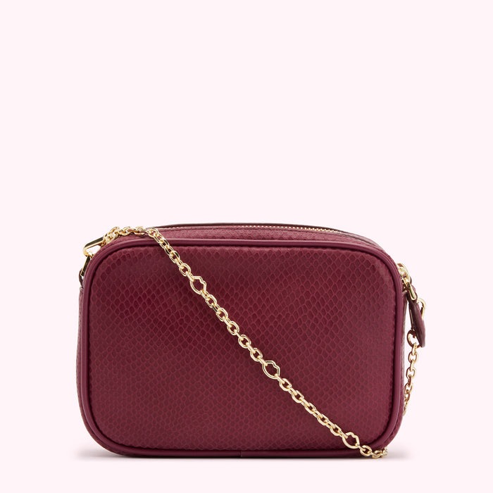A burgundy rectangular crossbody bag with a gold chain strap and snakeskin embossed texture.