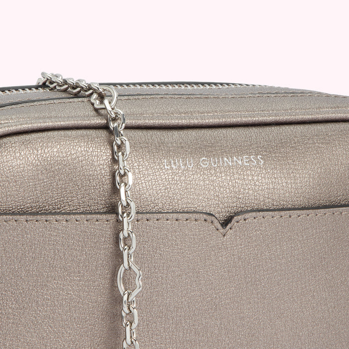 Close-up of a silver Lulu Guinness crossbody bag with a chain strap.