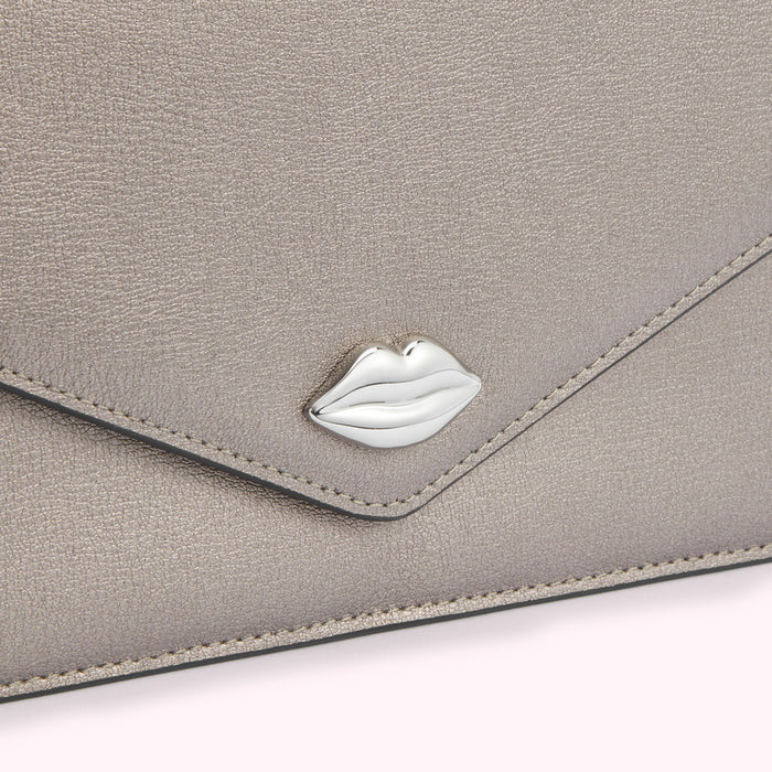 Close-up of a metallic silver envelope-style clutch with a silver lip-shaped detail.
