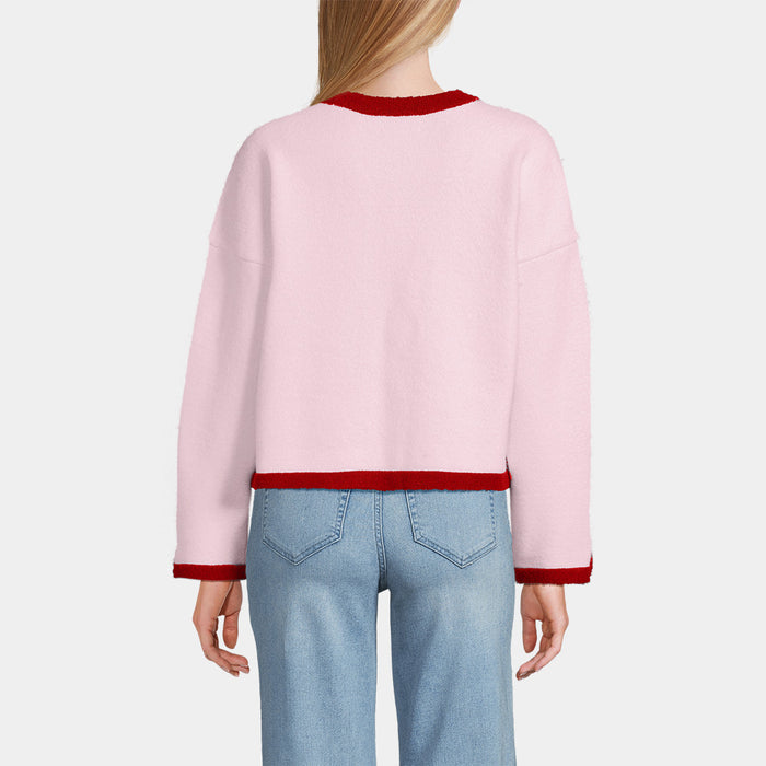 Person wearing a pink sweater with red trim and light blue jeans on a white background