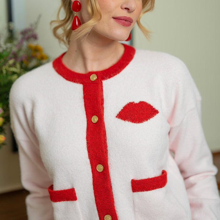 Women wearing a pink cardigan with red trim and knitted lip.