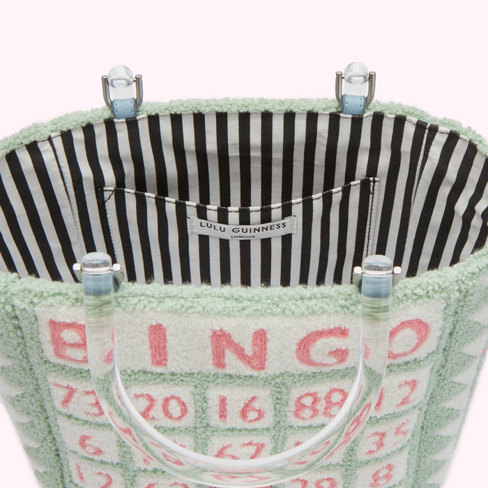 Interior view of a pale green Lulu Guinness Bingo tote bag with clear Perspex handles. The interior lining is black and white striped.