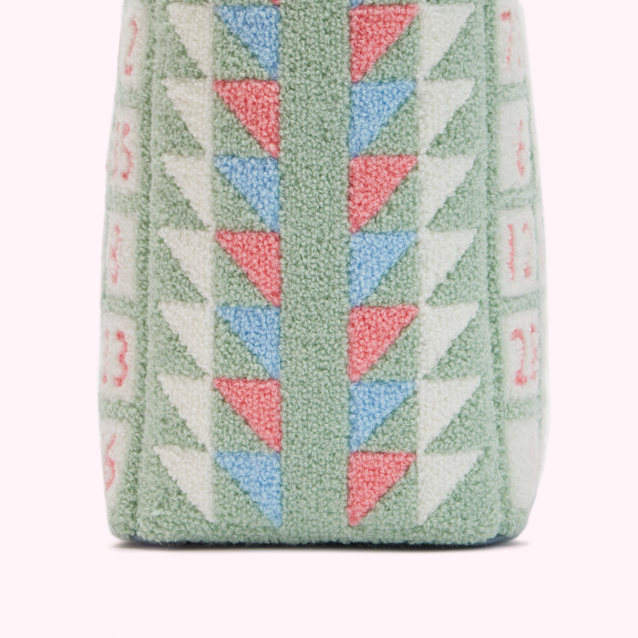 Close-up of the base of a sage green textile bag with pink, light blue, and white embroidered triangle patterns.