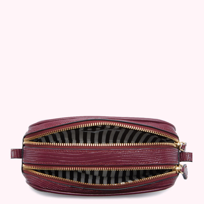 Burgundy crossbody bag open to reveal its two compartments and striped lining.