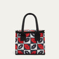 A square lunch bag with black handles, featuring a black, white, and red checkerboard pattern of lips on the front, set against a plain light beige background.