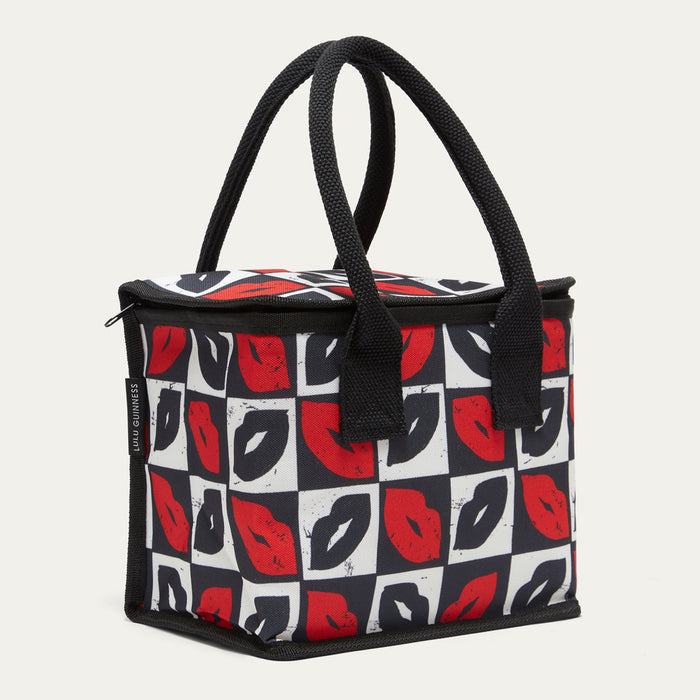 A square-shaped insulated lunch bag with black handles, featuring a black, white, and red lips pattern on a light gray background.