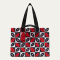 A tote bag with a black and white checkerboard pattern featuring red and black lips print, black shoulder straps, and a red hanging tag, shown against a light gray background.