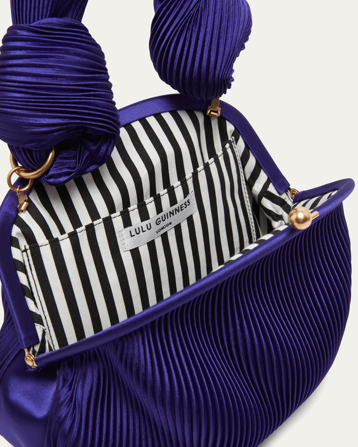Purple pleated handbag with a striped interior and Lulu Guinness label.