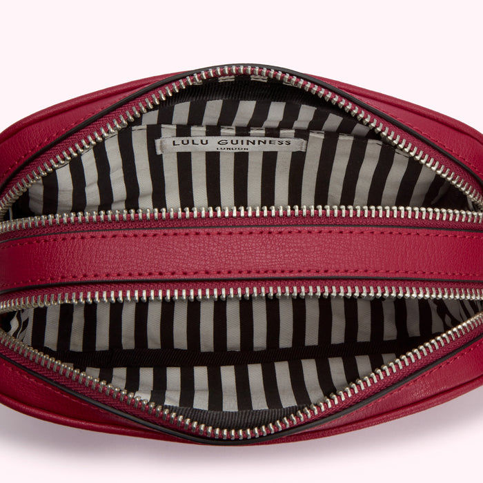 Interior of a crimson Lulu Guinness London crossbody bag with black and white striped lining.