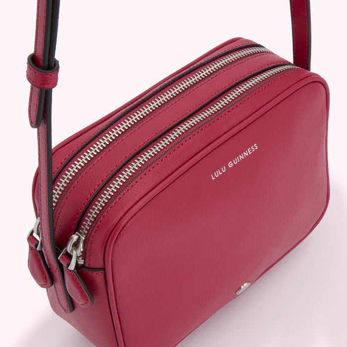 Red Lulu Guinness crossbody bag with two zippers.