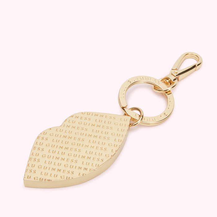 Gold lip-shaped keychain with the words "GUINNESS" and "LULU" repeated on it.