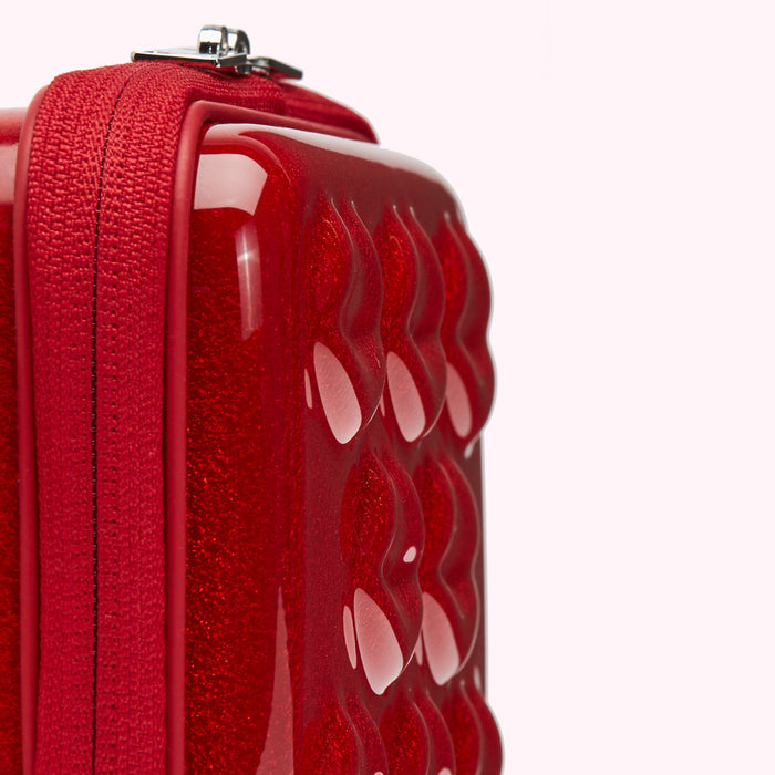Close-up of a red, textured, glossy cosmetic bag with a zipper.