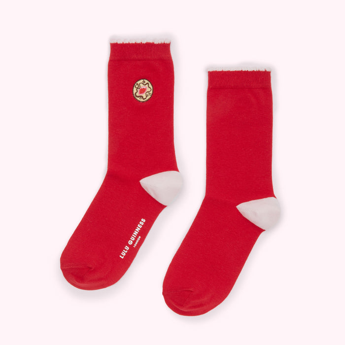 Pair of red socks with a small biscuit design and Lulu Guinness branding.