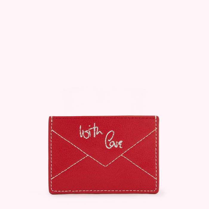 Red leather cardholder with "With Love" embroidered on the front in off-white thread, designed in the shape of an envelope.