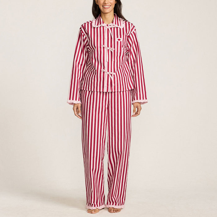 Woman wearing red and pink striped pyjamas standing against a plain wall.