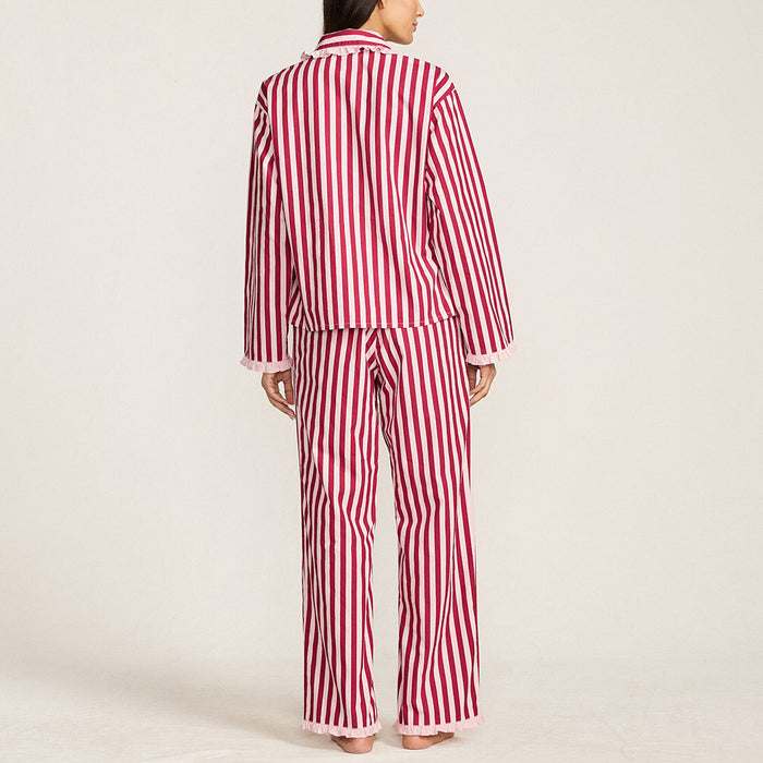 Woman wearing red and pink striped pyjamas standing against a plain wall.