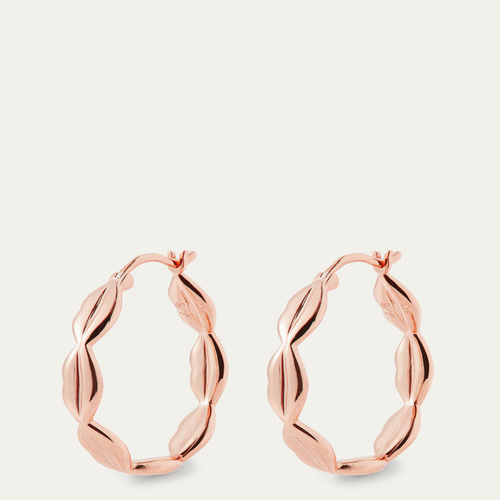 Rose gold hoop earrings on a light beige background