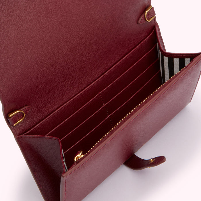 Burgundy leather wallet open to reveal multiple card slots and a zipped compartment; gold-toned hardware.