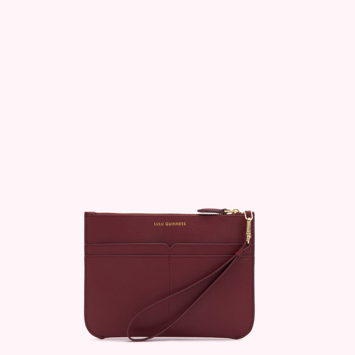 Burgundy leather zip-around clutch with wrist strap and gold Lulu Guinness logo.