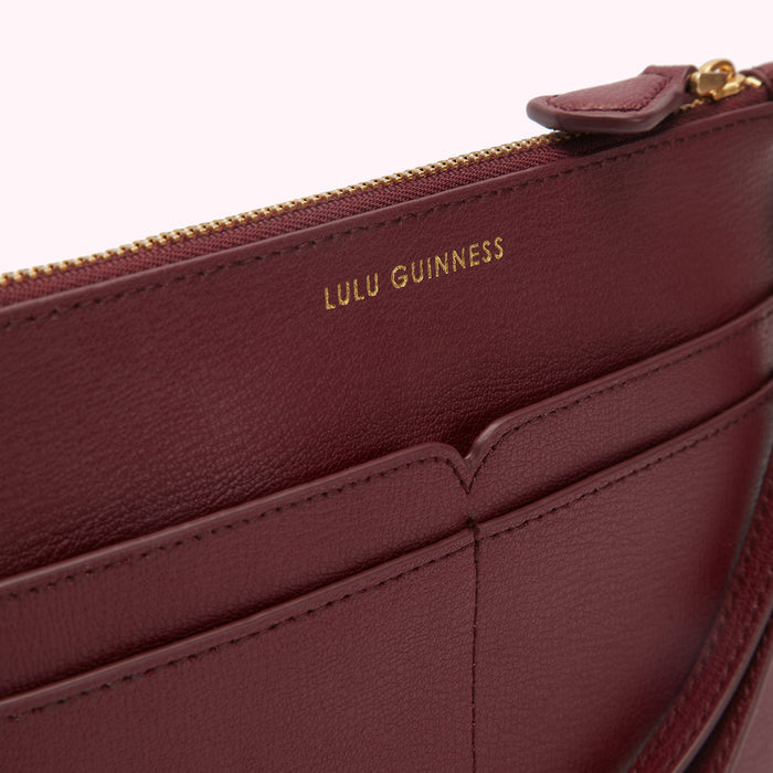 Close-up of a burgundy Lulu Guinness zip-around wallet with gold zipper and embossed branding.