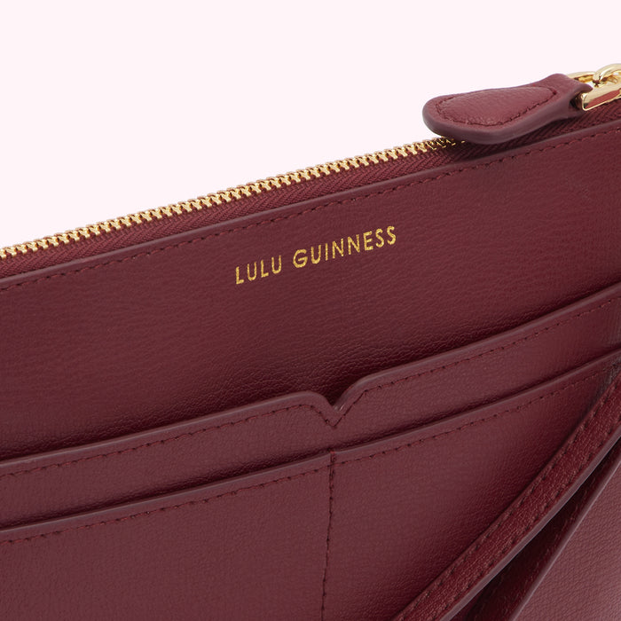 Close-up of a burgundy Lulu Guinness zip-around wallet showing the interior with gold zipper and branding.