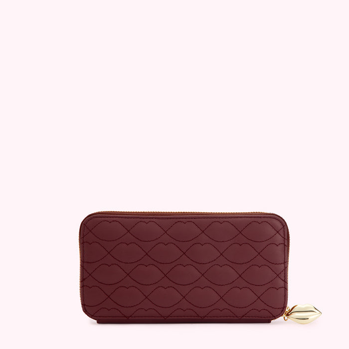 Burgundy zip-around wallet with embossed lip pattern and gold lip charm.