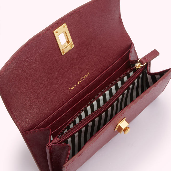 Open burgundy Lulu Guinness wallet with gold accents and black and white striped interior.