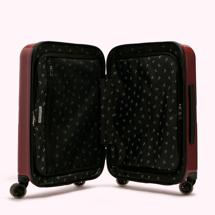 Open burgundy suitcase with black patterned lining.