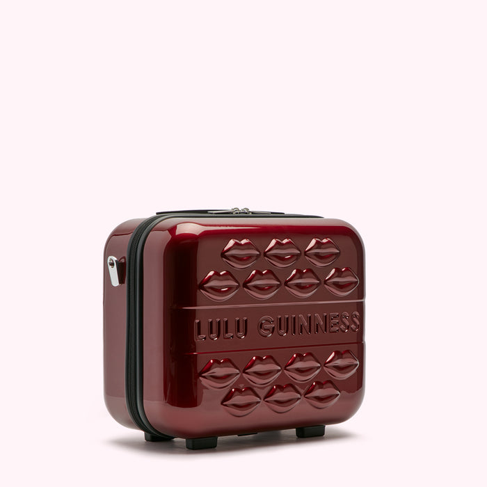 A dark red Lulu Guinness makeup case decorated with embossed lips.