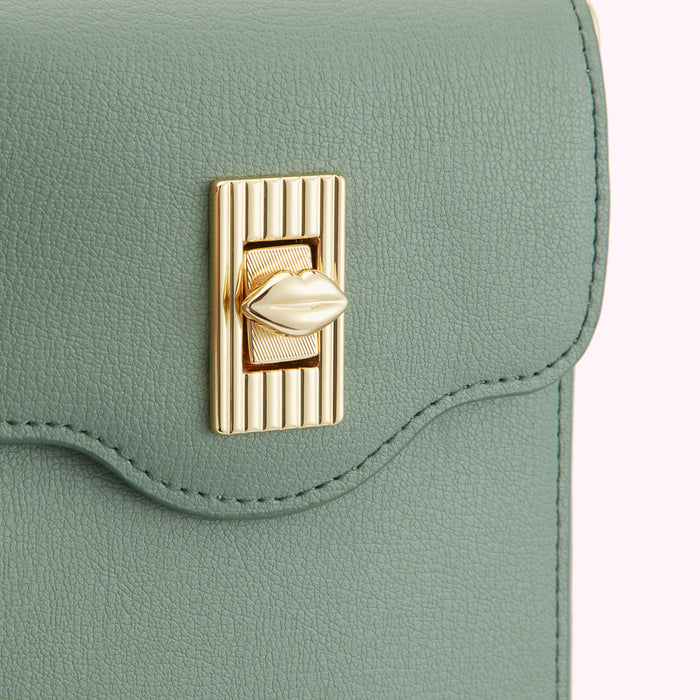 Close-up of a sage green purse with a gold lip-shaped clasp.