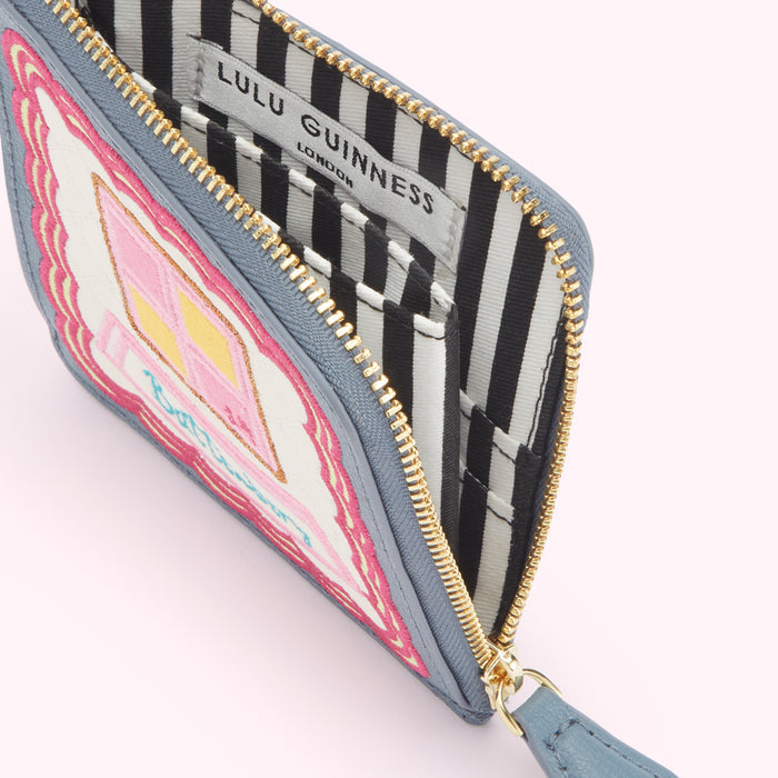 A grey Lulu Guinness zip-around purse with an embroidered pink and yellow house design on the front, partially open to show the black and white striped interior lining.